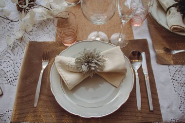 Tabağa çatal, bıçak, kaşık, bardak ve iki farklı bardakla peçete koyun. Yemek masaları için Noel süslemesi