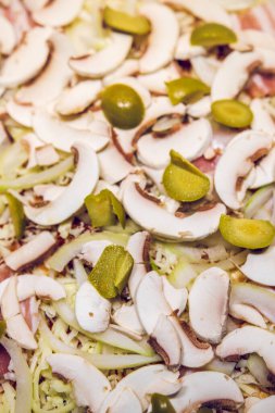 Pişirmeden önce sosisli, soğanlı, zeytinli ve jambonlu ev yapımı pizza..