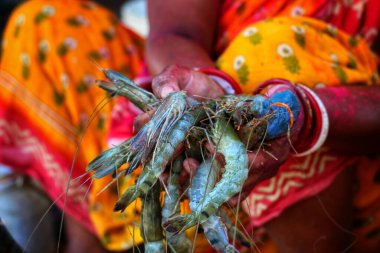 Kadın arka planda bir sürü karides tutuyor.