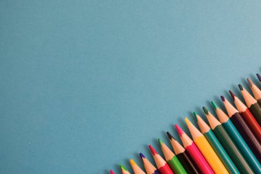 Resim veya metnin için kopyalama alanı olan mavi kağıt arkaplan üzerine renkli kalemlerin yakın plan görüntüsü. Yüksek kalite fotoğraf