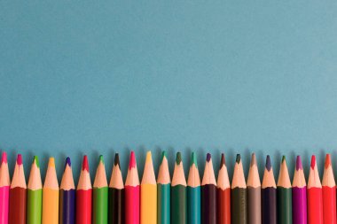 Resim veya metnin için kopyalama alanı olan mavi kağıt arkaplan üzerine renkli kalemlerin yakın plan görüntüsü. Yüksek kalite fotoğraf