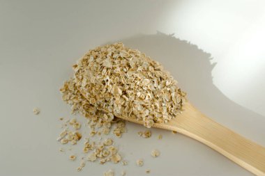 Beyaz masadaki kuru yulaf ya da tahta kaşıkta yulaf ezmesi. Protein ve lifle ilişkilendirilmiş besin açısından zengin bir besindir. - Evet. Yüksek kalite fotoğraf