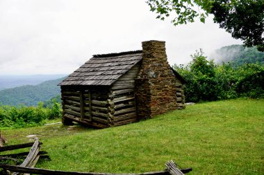 Log settler's cabin built by W. J. Trail at the Smart View Recreation Area on the Blue Ridge Parkway. Low rolling clouds on Appalachian Mountains. Pioneer dwelling of one room built in early 1890s.