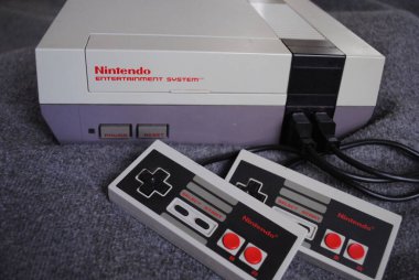 Nintendo Entertainment System (NES), Nintendo tarafından üretilen 8-bit üçüncü nesil ev oyunu konsolu. NES Denetim Güvertesi ev oyun konsolu denetleyiciler ile.