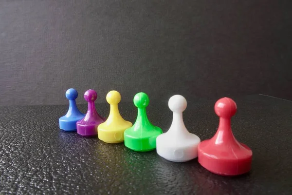 Plastic board game pawns or tokens. Blue, purple, yellow, green, white and red.