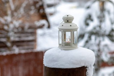 Mum alevini koruyan şeffaf bir vücudu olan eski bir fener. Taşıyabileceğiniz ya da asabileceğiniz saplı bir lamba. Kışın bahçesinde yanan bir mum olan klasik bir lamba. Kış partisi dekorasyonu. Seçici odak.