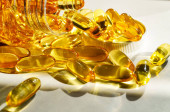 Omega 3 pilulky na rybí tuk. Kopírovat pozadí prostoru. Žluté lesklé tobolky vytékající z lahvičky.