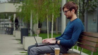 Genç iş adamı şehir parkında otururken dizüstü bilgisayar kullanıyor. Öğrenci bankta ders çalışıyor. Dizüstü bilgisayarda çalışan girişimci.