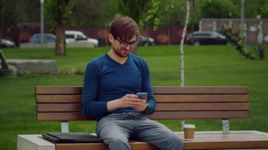 Portre, açık havada cep telefonu kullanarak yazan adama odaklanmış. Yavaş çekim.