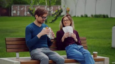 Parkta atıştırmalık bir şeyler alan genç iş adamları. Dışarıda yemek yiyorum. Yemeğin tadını çıkarıyorum. Güzel çerezler kokuyor..