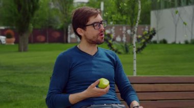 Sağlıklı Yemek Yiyen Yakışıklı Adam. Sağlıklı atıştırmalık olarak elma. Meyvenin tadını çıkarıyorum. Erkek portresi parkta atıştırmalık..