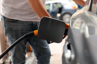 Benzin istasyonunda benzinle dolu bir araba. Benzin istasyonu pompası. El Adam istasyonda yakıt doldurup depoyu dolduruyor..