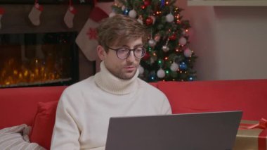 Yılbaşı Selfie Video görüşmesi. Genç adam ailelerden bahsediyor, video aracılığıyla arkadaşları arıyor, merhaba diyor ve mutlu noeller diliyor..