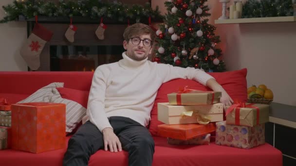 Pohledný Muž Hledící Kameru Sedící Gauči Dárkovými Krabicemi Postřelen Vánoční — Stock video
