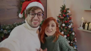 Âşık genç çift akıllı telefon kullanarak aileleriyle ya da arkadaşlarıyla konuşuyorlardı. Video uygulaması ile Mutlu Noeller diliyor. Modern teknoloji kolay ve konforlu kullanım, yeni yıl 2022 Uzaktan konsept tebrikler