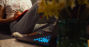 Dizüstü bilgisayarla not yazan genç bir kadın..