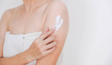 Kadın krem sürüyor, koluna krem sürüyor, beyaz arka plan, güzellik konsepti..