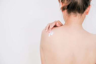 Kadın krem sürüyor, beyaz arka planda losyon sürüyor, güzellik konsepti..