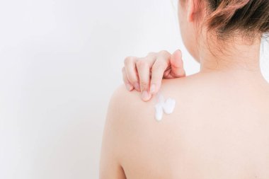 Kadın krem sürüyor, beyaz arka planda losyon sürüyor, güzellik konsepti..