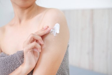 Asyalı kadın doğal krem sürüyor, kadın kolunu kozmetik krem, spa ve manikür konseptiyle nemlendiriyor..