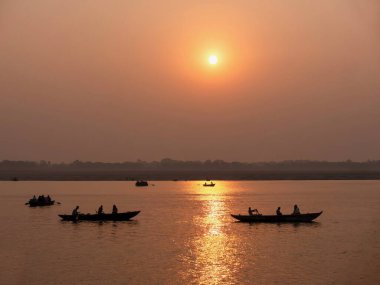 Varanasi, Hindistan 'da gündoğumunda Ganj Nehri' nde kürek çeken tahta botlar..