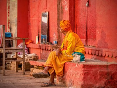 Varanasi, Hindistan - 13 Kasım 2015. Geleneksel kıyafetler giyen Hintli bir berber, müşterileri açık havada bekliyor..