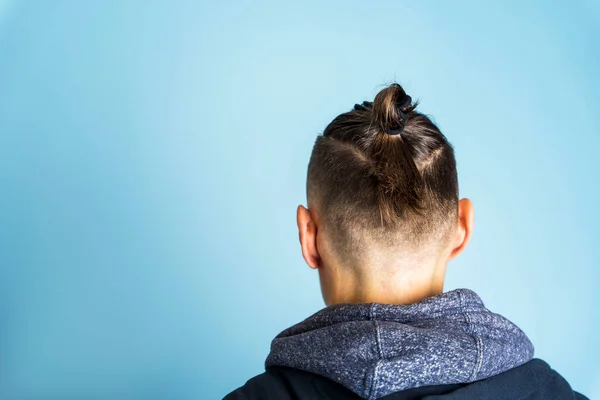 Yan profil fotoğrafını kapat. Saç stili Top Knot ya da Erkek Çöreği olan bir adam mavi arka planda, erkek saç stili, saç bakımı