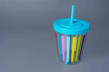 Gri arka planda pipetli renkli neşeli bir fincan..