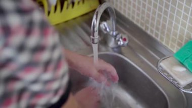 Bir kız mutfakta lavaboyu deterjanla yıkıyor, musluktan su akıyor, ev temizliği konsepti, yaşam tarzı...