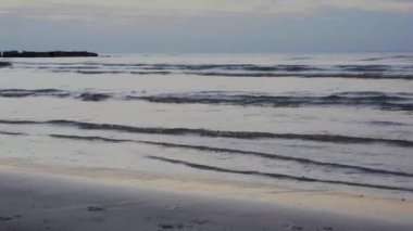 Koyun küçük dalgaları kumlu bir sonbahar plajını kaplıyor, denizde bir dalga, sahilde küçük bir dalga...