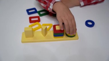 Çocuk ayırıcı yapıcıyı topluyor. Bulmaca çözücü, erken gelişim kavramı. Çocuk elleri bulmacayı masaya koydu. Çocuklar için sınıfları çal.