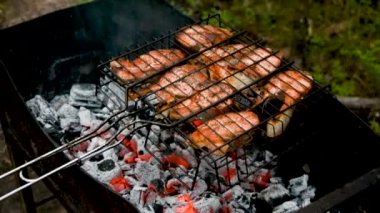 Balık parçaları ızgarada pişiriliyor, arka planda yanan odun ve kömür, balık barbeküsü, doğada pişirme, açık havada ızgara balık bifteği. Bahçede barbekü