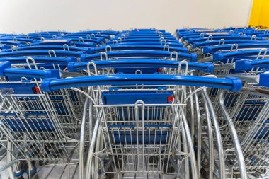 Tramvay hipermarkete park ediyor, açık mavi alışveriş arabaları, arka arkaya bir sürü boş alışveriş arabası.