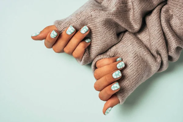 Mãos de mulheres bonitas com manicure colorido, vestida com uma camisola de lã quente — Fotografia de Stock