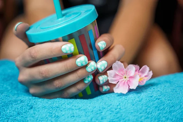 Mãos de mulheres bonitas com manicure colorido segurar um copo multicolorido com um tubo de beber — Fotografia de Stock