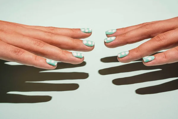 Duas belas mãos femininas com manicure colorido em tons turquesa estão alcançando um ao outro — Fotografia de Stock