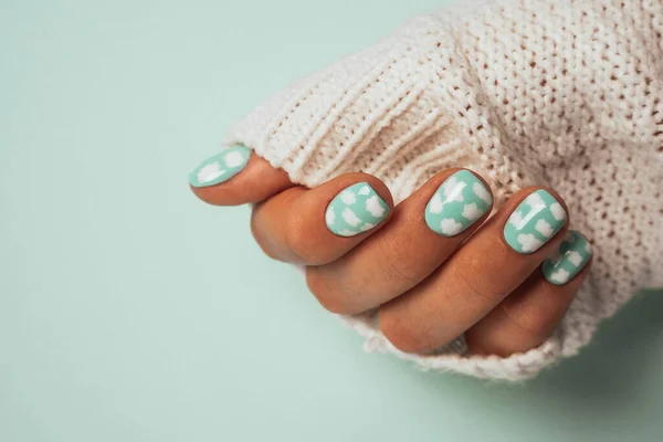 Beaux doigts féminins fins avec une manucure colorée dans la manche d'un pull en laine blanche chaude — Photo