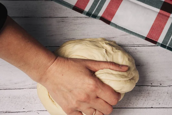 Şeflerin elleri mutfak masasında taze pizza hamuru hazırlar ve yoğurur.