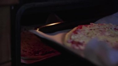 Kadınların elleri fırına pizza koyar, peynirli pizza pişirir.