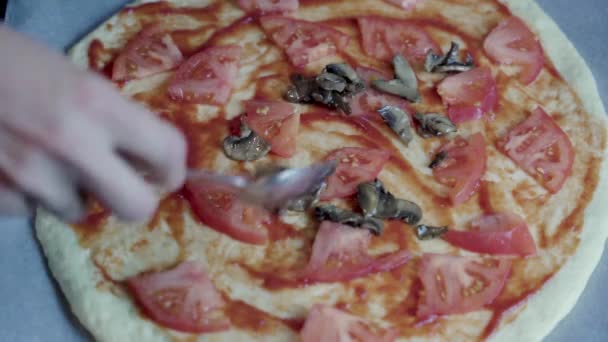 Gotowanie pizzy z grzybami w domu, dłoń kobiet kładzie grzyby na ciasto pizzy — Wideo stockowe