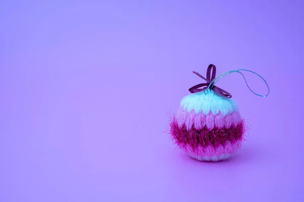 Boule de Noël tricotée, douce et colorée à la main sur un fond violet clair — Photo