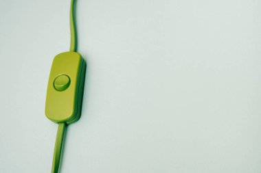 Turkuaz arka planda anahtarı olan yeşil elektrik kablosu