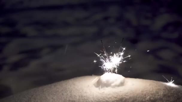 Sparklers geplaatst in de sneeuw. Heldere vonken van sterretjes in het donker. — Stockvideo