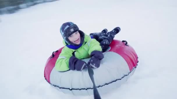 Funny Caucasian boy 5 years old rides in winter on a big inflatable cheesecake — Vídeo de Stock