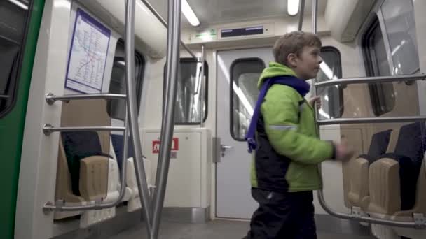 Zabawny biały chłopiec 5 lat jedzie w pustym wagonie metra — Wideo stockowe