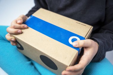 Çocuk, içinde teslimat servisinin gönderdiği bir hediye olan karton bir kutu tutuyor. Yakın plan.