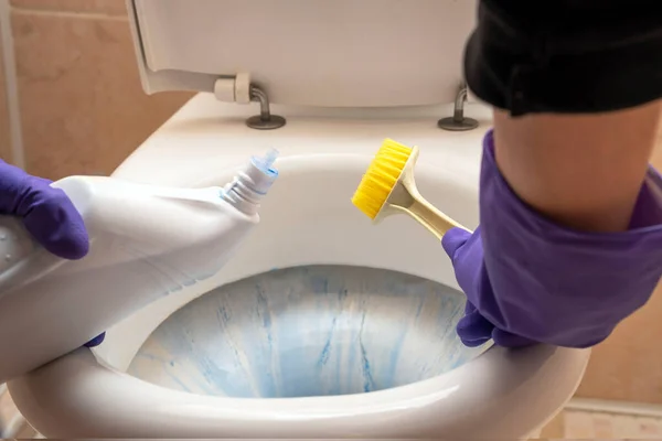 As mãos das mulheres lavar o banheiro no banheiro com detergente, uma escova — Fotografia de Stock