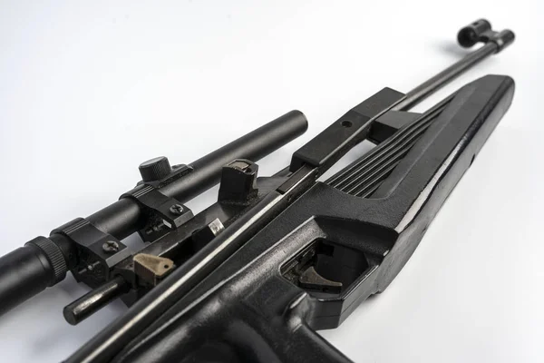 Puška s optickým zaměřovačem leží na bílém stole, zbraně — Stock fotografie