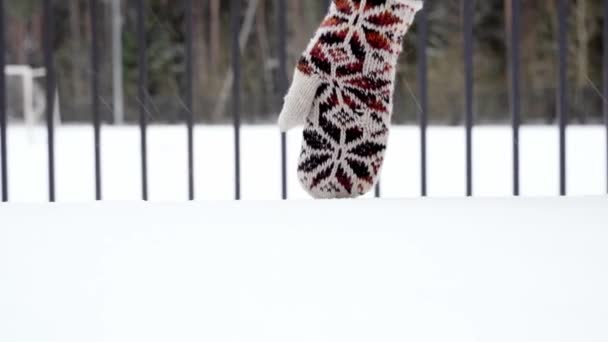 Ręka kobiety ubrana w wełnianą rękawicę biegnie przez świeży biały śnieg. — Wideo stockowe