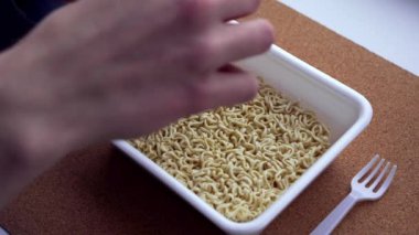 Bir gencin elleri kurutulmuş sebzeleri Çin eriştesinin içine döker. yakın plan